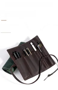 Detail of leather roll pencil case showing internal slots for pens and key decoration