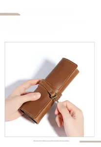 Detail of vintage brown leather pencil roll featuring a retro key charm and wrap-around strap
