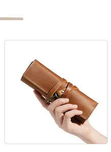 Detailed view of genuine brown leather pencil roll with vintage key buckle and strap