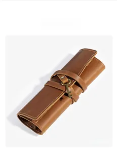 Detail of brown genuine leather roll pouch featuring vintage key charm and white stitching