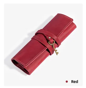 Macro detail of red genuine leather pen roll with vintage bronze key pendant