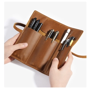Close-up of handmade leather roll pencil case showing internal slots for pens and brushes