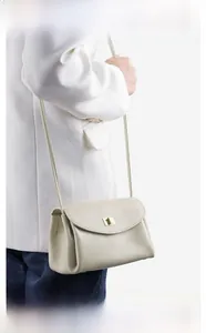 Detail of elegant beige pebbled leather crossbody bag with gold metallic twist lock
