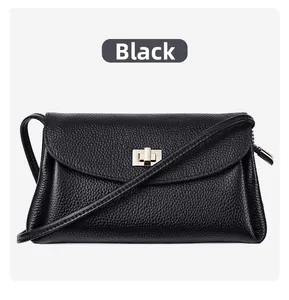 Detail of black pebbled leather crossbody bag with elegant gold-tone metal twist lock