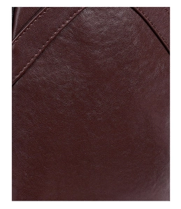 Macro shot of dark brown pebbled leather texture with fine stitching on crossbody bag