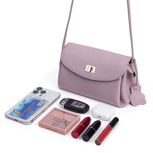 Mini lavender leather crossbody bag with gold lock and daily essentials on white background