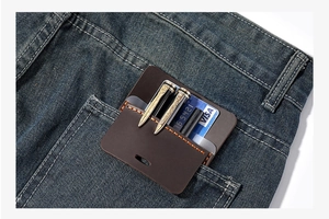 Close-up of a brown leather pocket organizer with orange stitching in a blue jean pocket