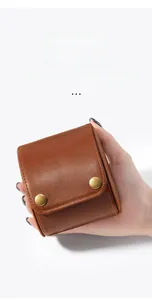 Close-up of a vintage brown leather watch pouch held in hand with dual brass snap buttons