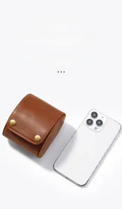 Compact brown crazy horse leather watch pouch with dual gold metal buckles next to a phone