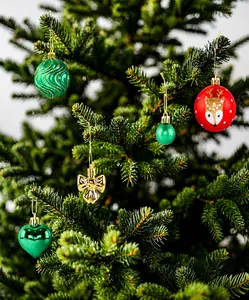 Detail van rode rendierballen en groene ornamenten op een versierde kerstboom