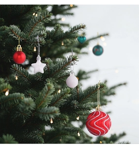 Detalle de bolas de Navidad rojas y rosas con estrellas blancas en un árbol festivo