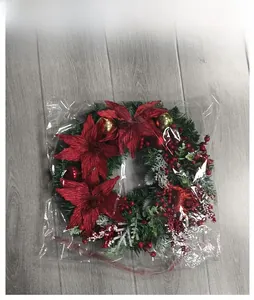 Detail view of Christmas wreath with pine needles and red poinsettia in clear packaging