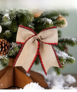Close-up of burlap Christmas bow with red and black plaid trim hanging on a tree