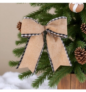 Close-up of rustic burlap Christmas bow with black and white plaid edges on a tree