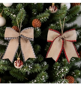 Detail view of rustic burlap Christmas bows with plaid edges hanging on a festive tree branch