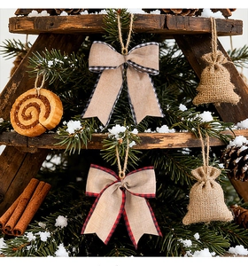 Rustic burlap Christmas bows and pouches hanging on a snow-covered tree branch