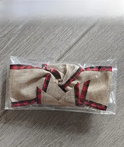 Detail view of red and black plaid faux burlap bow decoration in transparent packaging