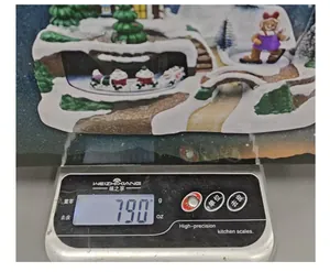 Detailed view of musical Christmas village house showing a net weight of 790 grams on a scale