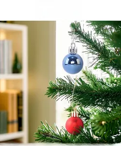 Detail of red matte and blue glossy Christmas ball ornaments hanging on a green tree