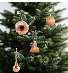 Detailed view of bronze Christmas donut and lucky bag ornaments hanging on a green tree branch