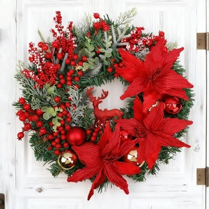 Christmas wreath with reindeer, pine needles and red poinsettia hanging on a white door