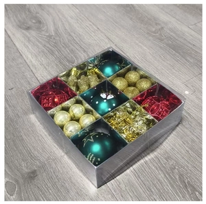 Detalle de set de bolas de Navidad rojas verdes y doradas en una caja de regalo clara