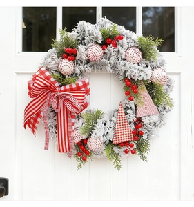 Detail of Christmas wreath with red berries and plaid bows on white wooden door