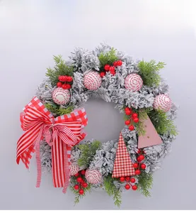 Detail of flocked Christmas wreath with red berries, striped ornaments and a plaid bow