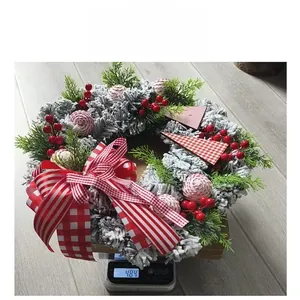 Detail showing Christmas wreath weight at 484g with snowy pine needles and red bow