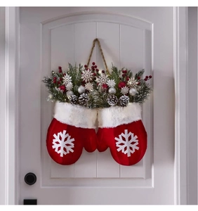 Detailopname van een kerstkrans met wanten, dennenappels en rode bessen op deur