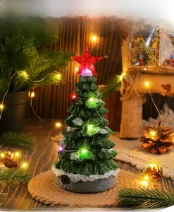 Detail of a glowing Christmas tree music box with LED lights and snow flocking on base