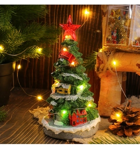 Close-up of glowing Christmas tree music box with warm LED lights and snowy resin detail