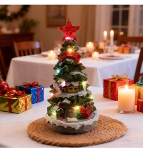 Detail of a glowing Christmas tree music box with miniature house on a dining table