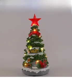 Macro shot of the glowing LED Christmas tree music box with miniature houses and snow