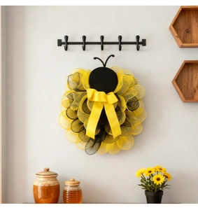 Detail eines kreativen Bienenkranzes aus Netzstoff mit gelber Schleife und Sonnenblumen