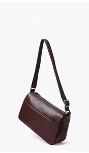 Detail of adjustable textile shoulder strap and silver metal buckle on a dark brown bag