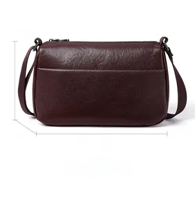 Detail view of burgundy leather crossbody bag showing front pocket and 28cm width dimensions