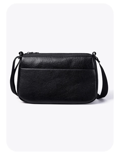 Close-up of black lychee grain leather crossbody bag showing metal zipper and back pocket
