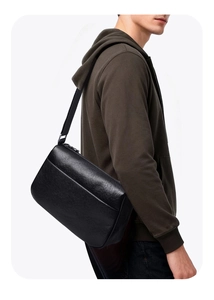 Close-up of black leather crossbody bag with lychee grain texture and silver metal zipper