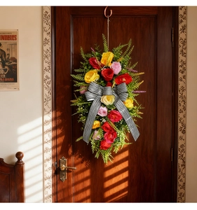 Detailed view of artificial flower door swag with large striped bow on wooden door