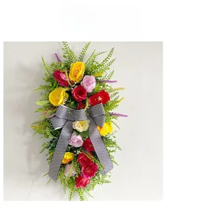 Detail of colorful artificial flower wreath with elegant black and white striped ribbon bow