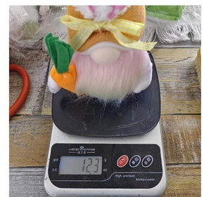 Détail d'un gnome de Pâques avec oreilles de lapin pesé sur une balance électronique