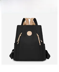 Front view of black waterproof nylon backpack with tan leather handle and round logo patch
