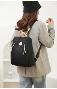 Modern black nylon anti-theft backpack for women styled on person in a minimalist setting