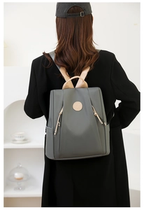 Detail of dark grey nylon anti-theft backpack with beige handles and tassel zipper pull