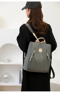 Rear view of a stylish dark grey nylon anti-theft backpack for women in a minimalist setting