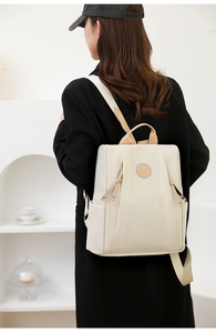 Detail view of lightweight beige nylon backpack with anti-theft design and sleek zippers
