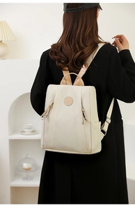 Detail view of cream white nylon backpack showing leather trim and contrast straps on model