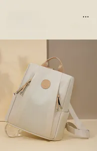 Detail of beige anti-theft nylon backpack featuring round embossed floral logo and side pockets