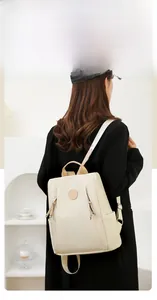 Back view of a beige anti-theft nylon backpack with leather handles on a model